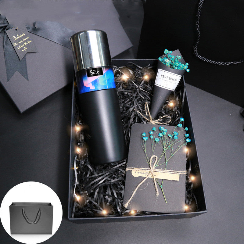 Black vacuum bottle in gift box with string lights and small teal flowers
