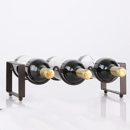 Black metal wine bottle rack with three curved slots, holding three bottles