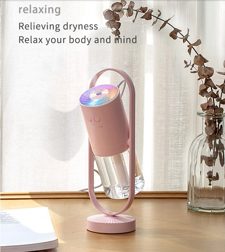 Pink USB air humidifier on desk with glowing top and clear mist chamber