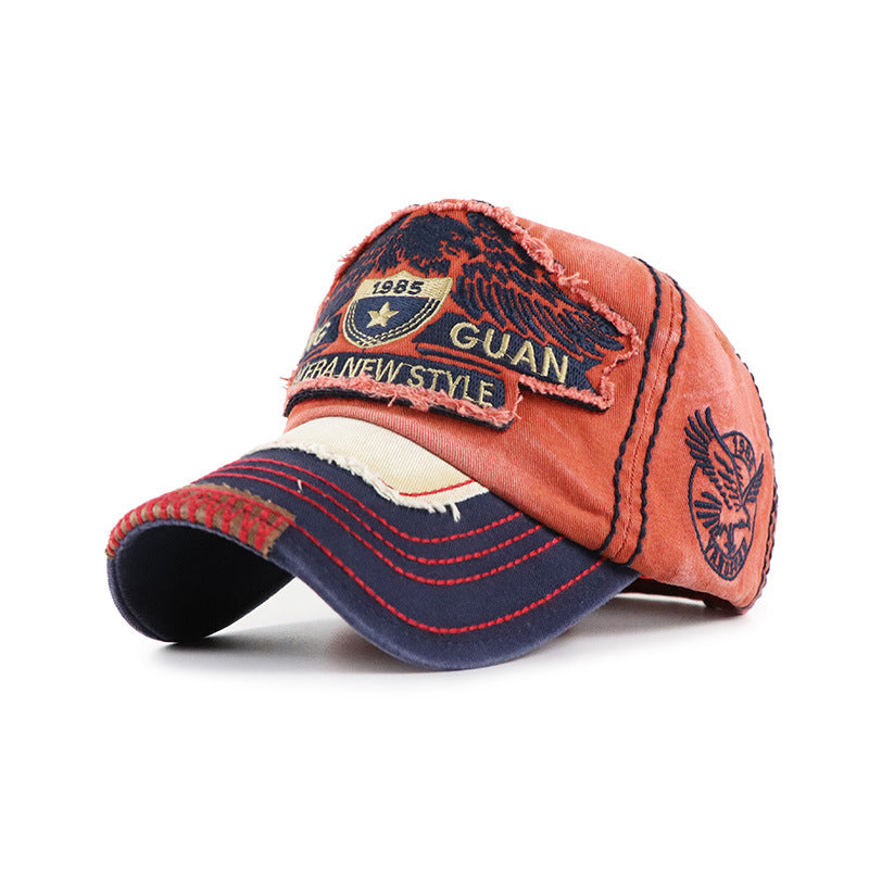 Baseball cap in rust red with dark visor; front GUAN embroidered patch and side logo