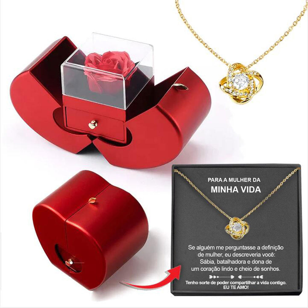 Red jewelry box with clear cover holding a red rose; gold heart pendant necklace shown