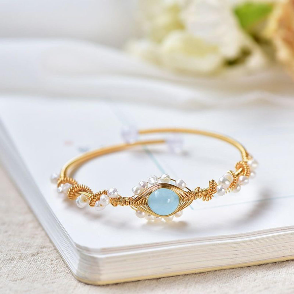 Gold pearl cuff bracelet with braided wire and round blue center charm
