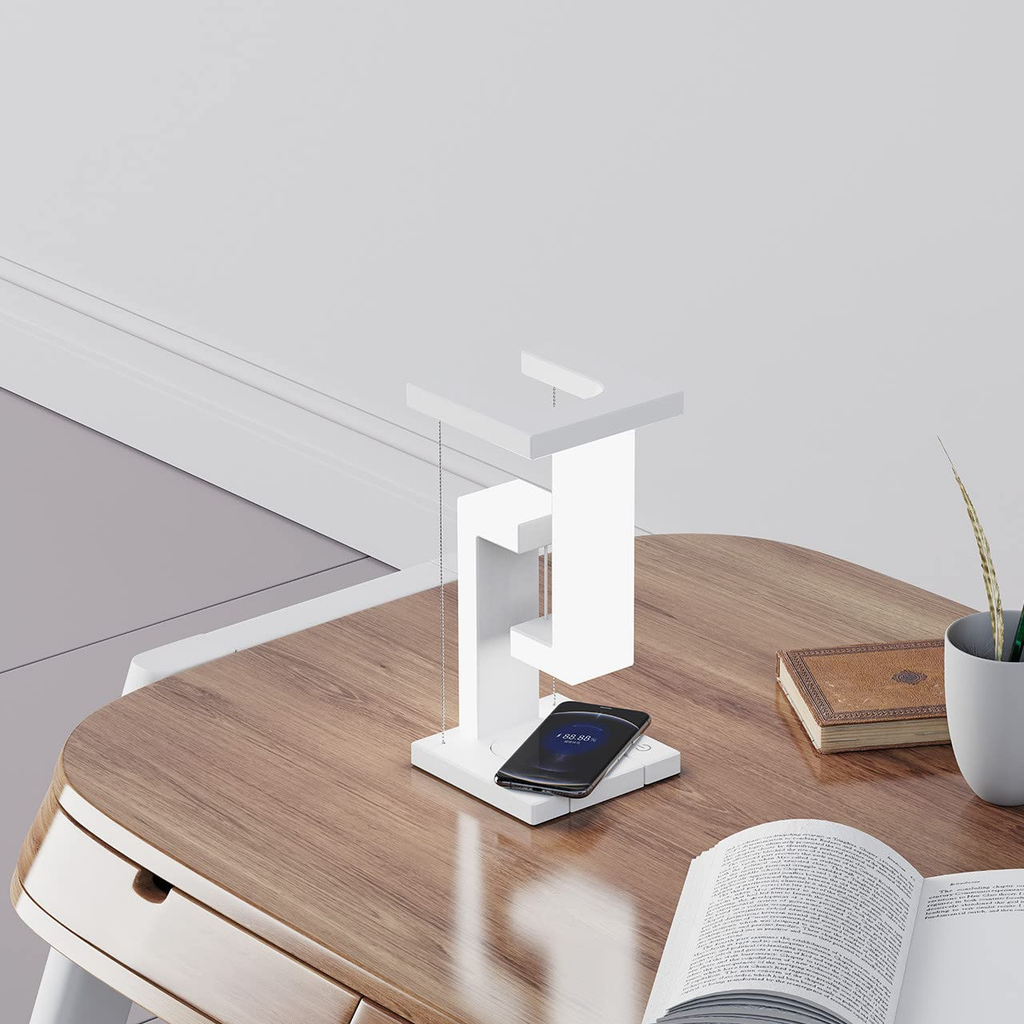White wireless charging table lamp with glowing top frame and phone charging pad on base