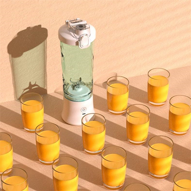 Portable blender with green blending cup and white base, shown with multiple juice glasses