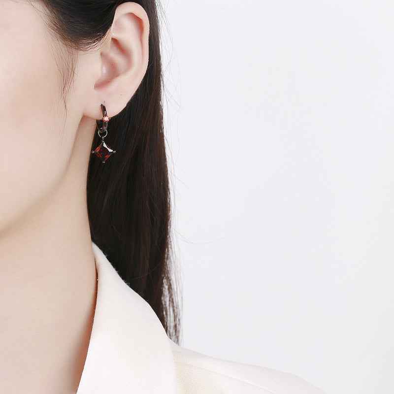 Red crystal dangle hoop earrings on ear with black metal