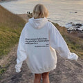 White plush hoodie with hood, drawstrings, kangaroo pocket, and printed back message