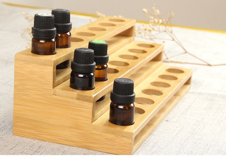 Wood essential oil bottle display rack with three tiers of round holes and several vials