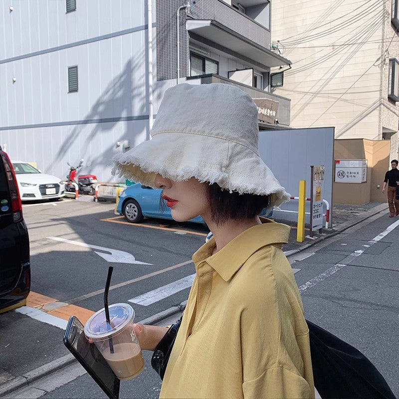 Light cream sun hat with wide brim and frayed trim, bucket-style crown.