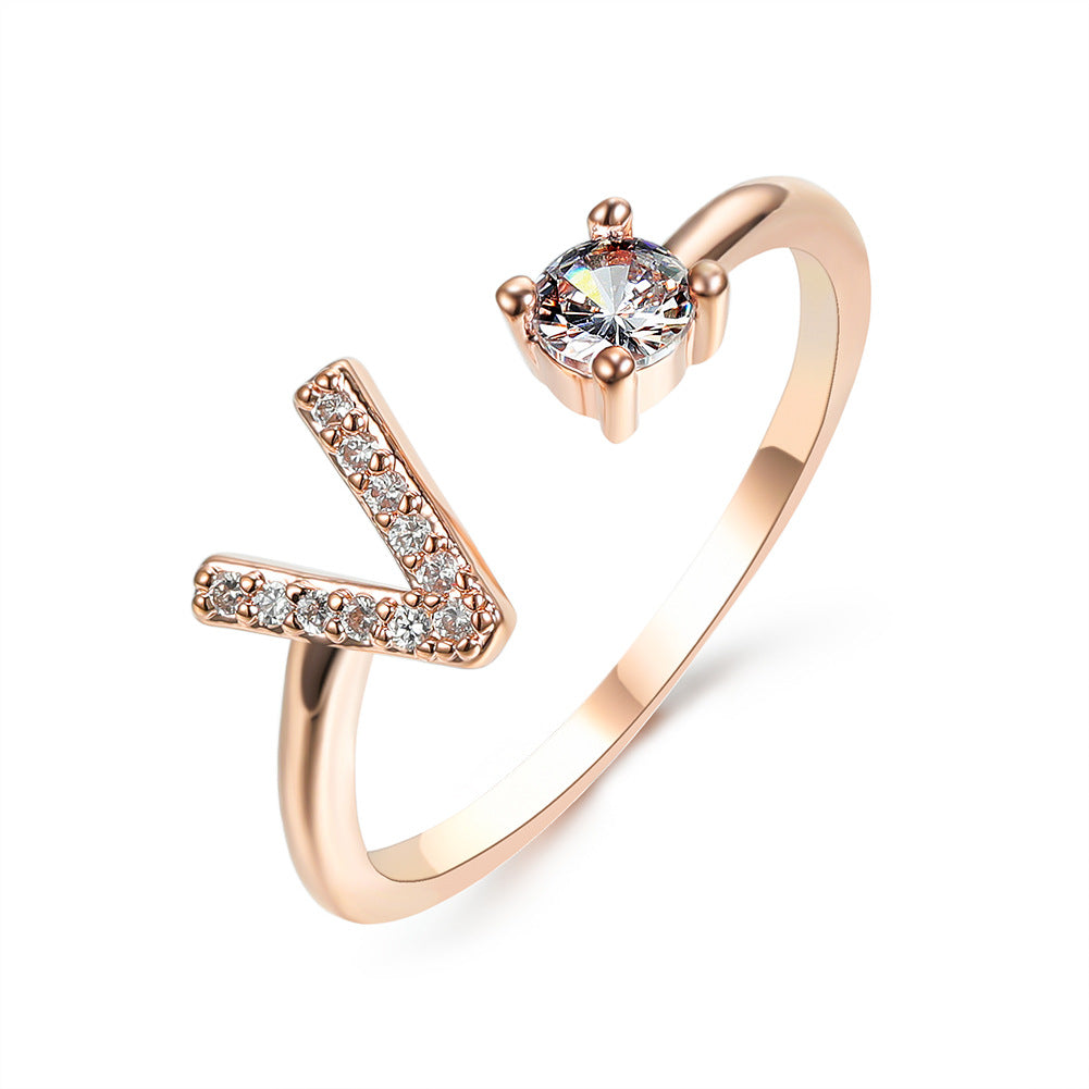 Rose gold adjustable initial ring with V-shaped letter and round center stone.