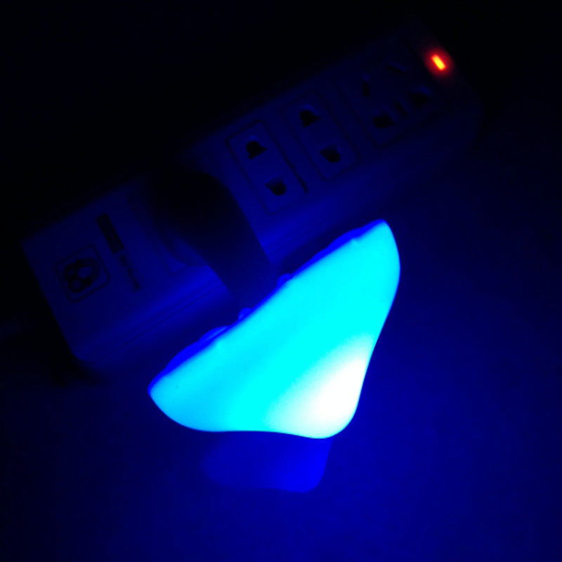 Plug-in mushroom LED night light glowing blue from wall outlet