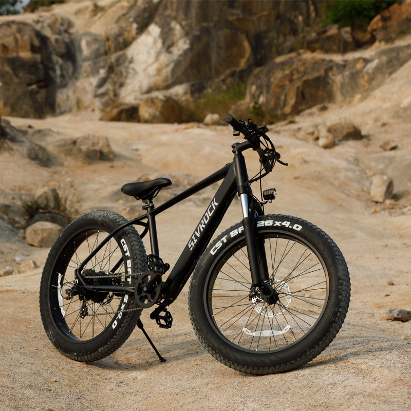 Black electric fat-tire e-bike with front suspension and 26x4.0 tires on dirt